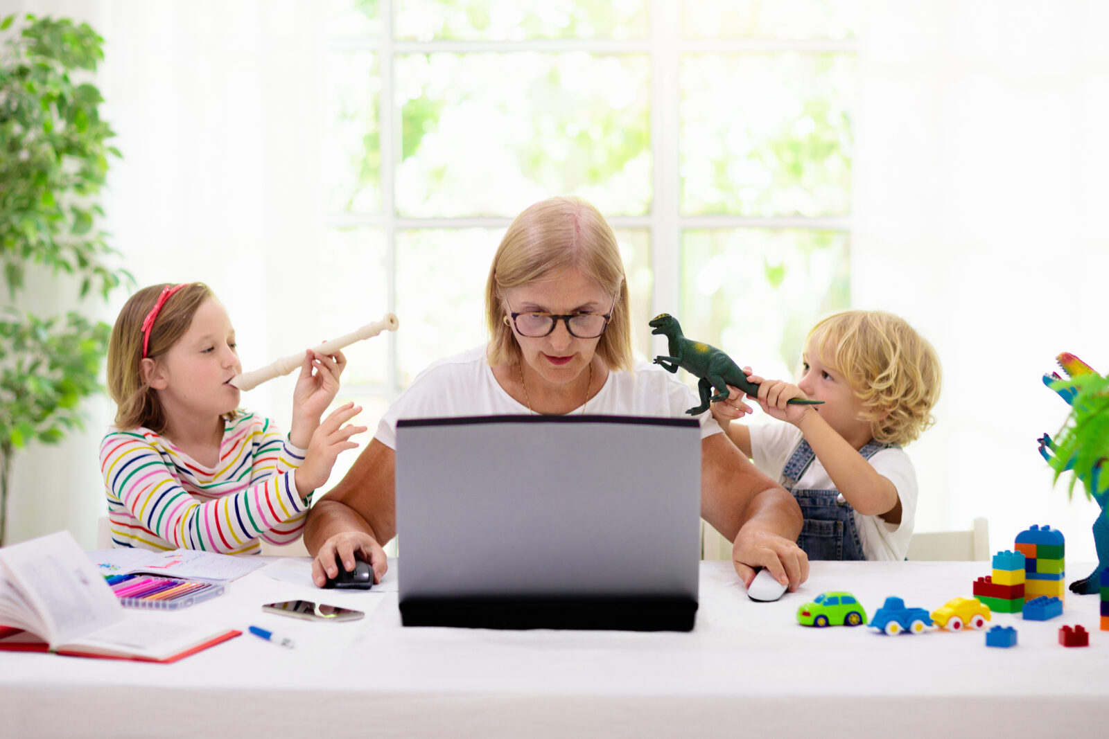 Mother works on computer while children do unorganized activities. 