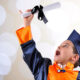 Little boy excitedly holding preschool diploma in the air