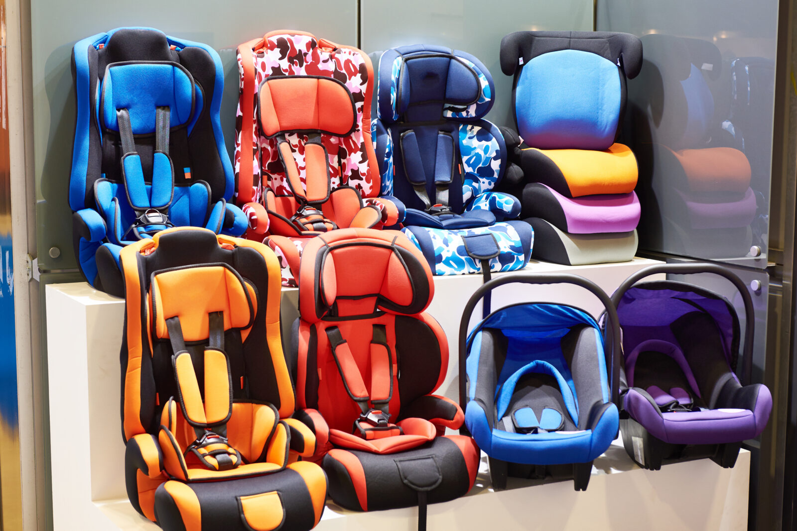 Series of carseats from rear facing to booster seats, line up in rows at a store