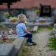 Little boy sitting on grave looking in to the distance