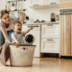 Mother pushing happy child around in a laundry basket for fun