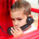 Child using a corded phone in a phone booth