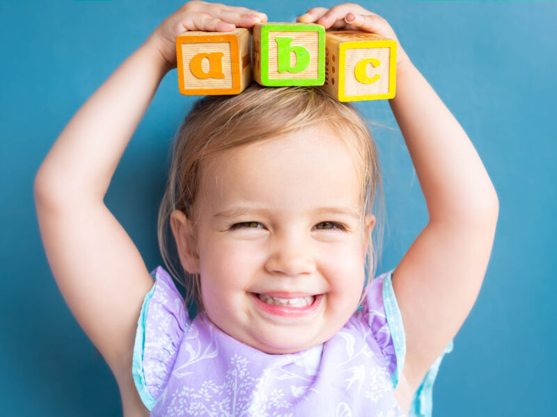 Happy little girl holding ABC blocks over her head