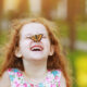 Happy little girl with a butterfly on her nose
