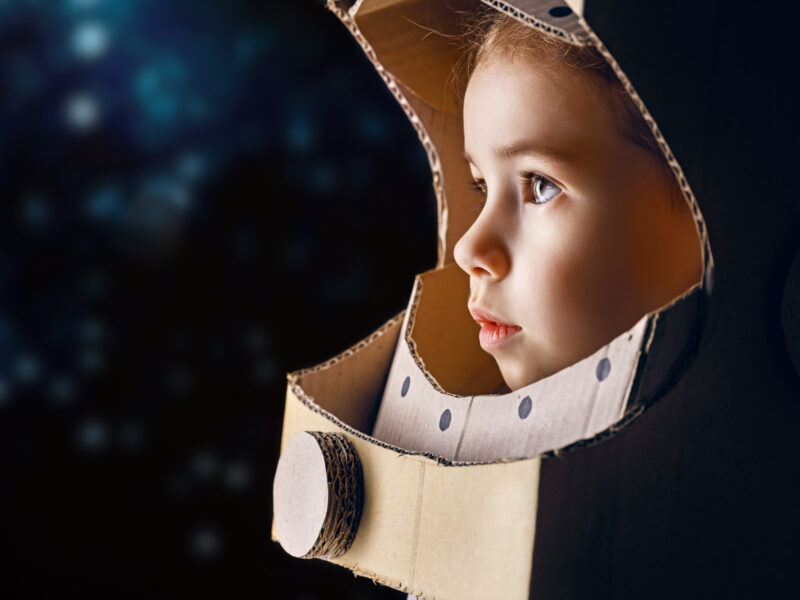 Child wearing an astronaut helmet made of cardboard