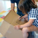 child writing name on cardboard box
