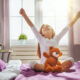 Little girl sitting in bed stretching her arms up happily