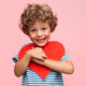 Happy little boy hugging a heart cut out